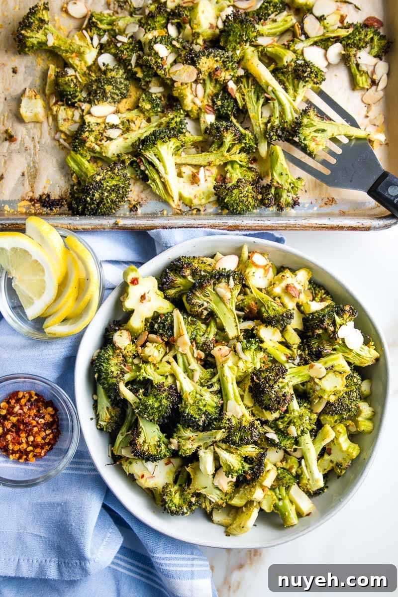 Spatula transferring roasted broccoli from sheet pan to bowl. 