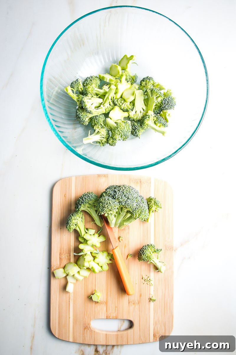Trimming broccoli into bite sized pieces and placing in a large bowl.