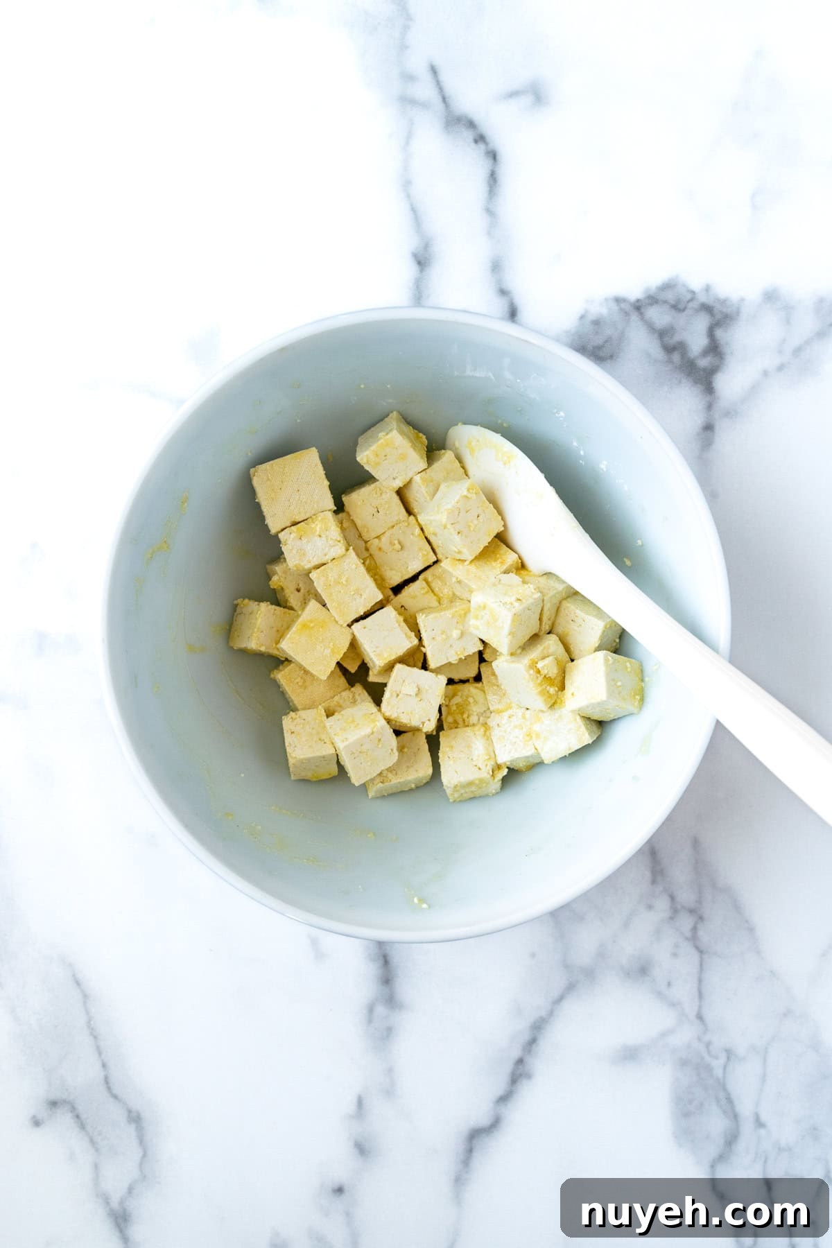 Crispy Orange Tofu Recipe with Sticky Citrus Glaze 4 Cubed Tofu with Olive Oil and Cornstarch in a Bowl.