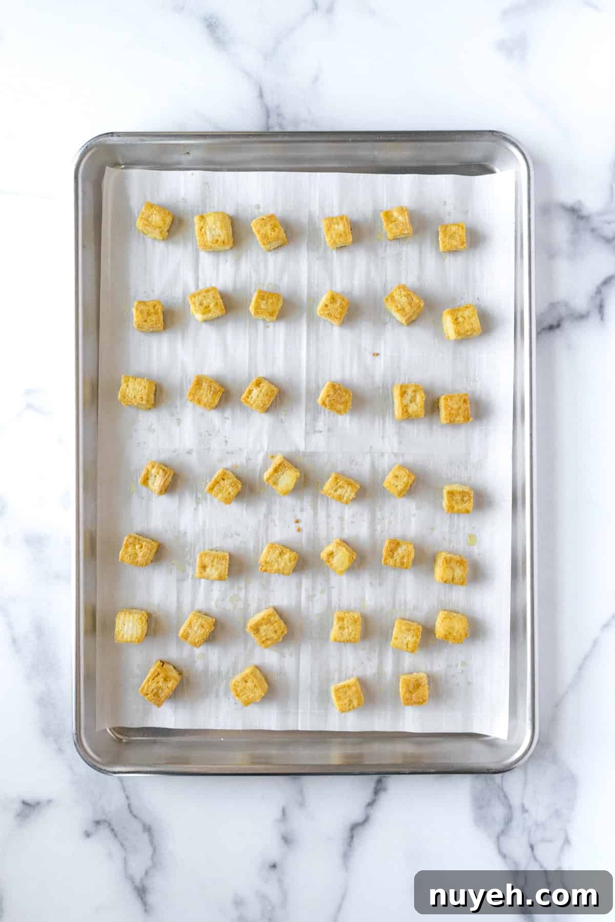 Crispy Orange Tofu Recipe with Sticky Citrus Glaze 5 Crispy Baked Tofu Cubes on a Baking Sheet.