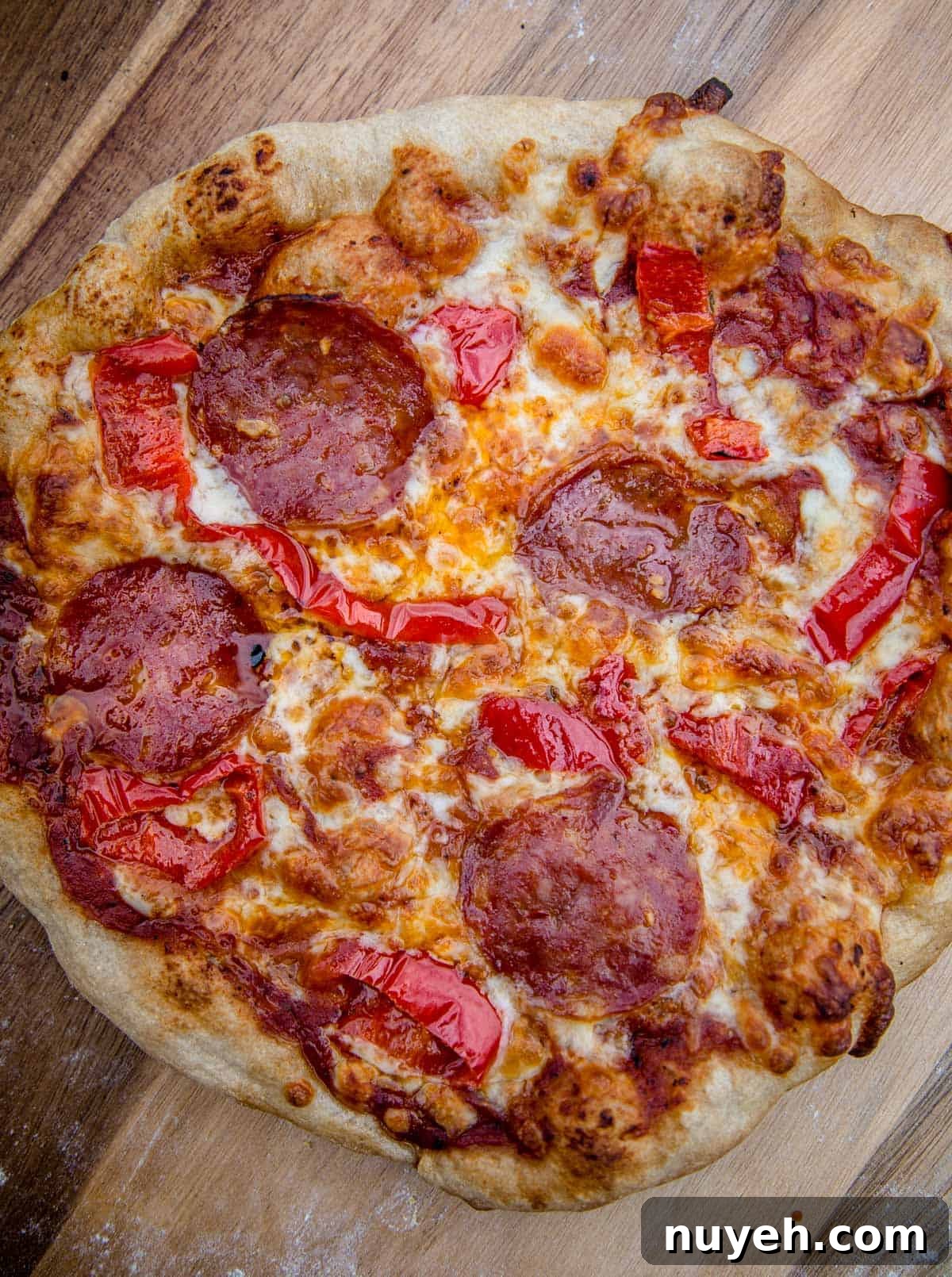A pepperoni and hot pepper pizza that was cooked on the grill