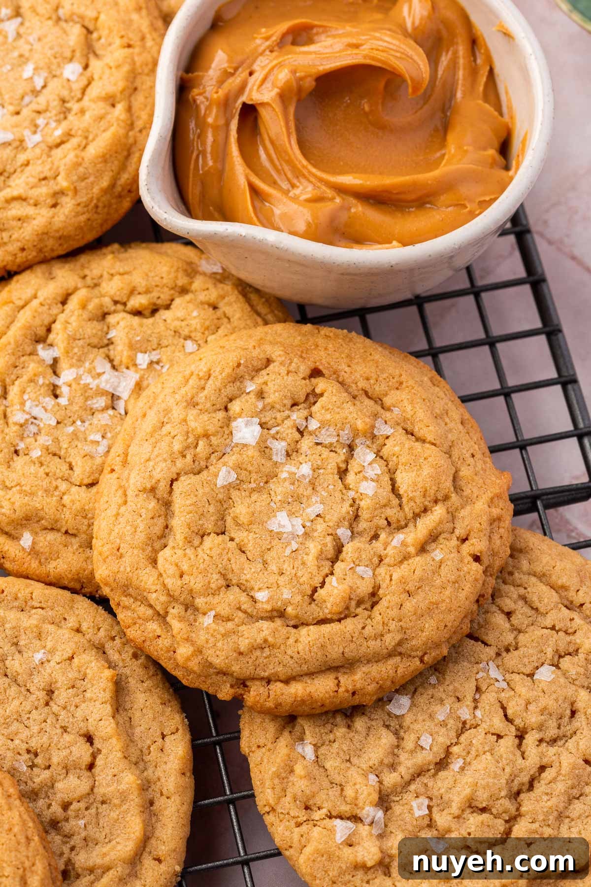 Gluten-free peanut butter cookies on a wire cooling rack with a small bowl of peanut butter to the side.
