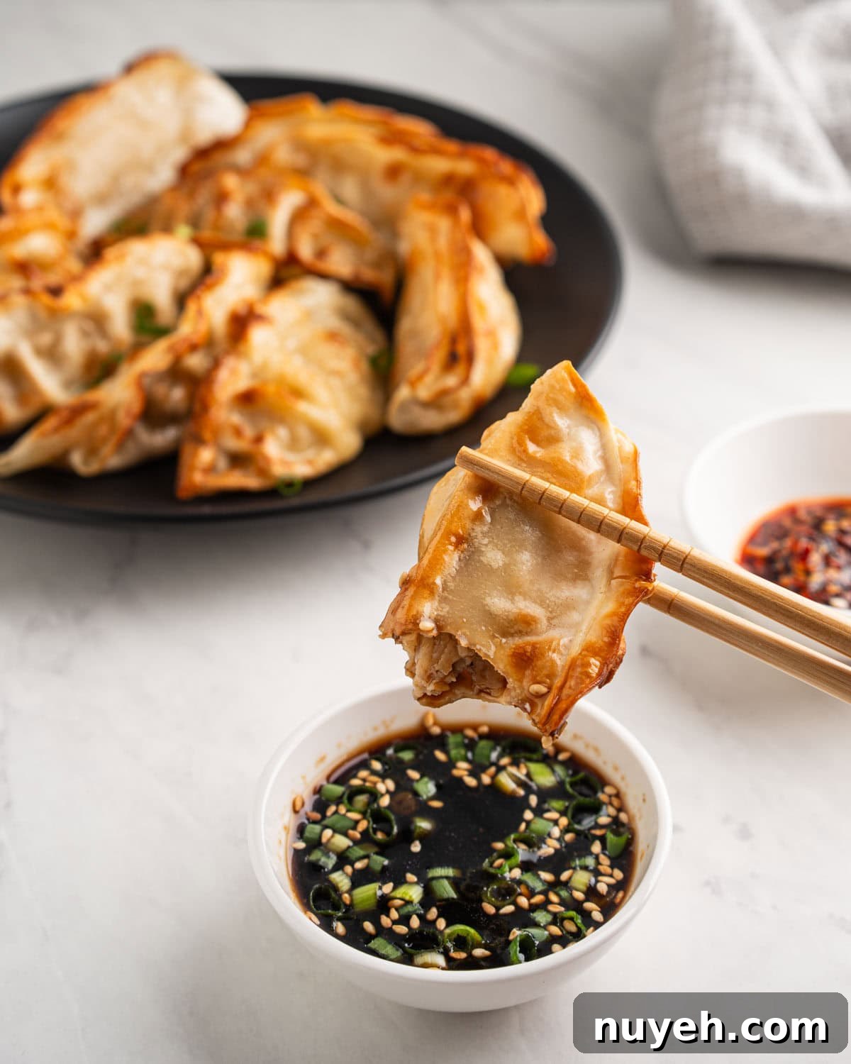 chopsticks dipping air fryer dumplings into soy sauce.