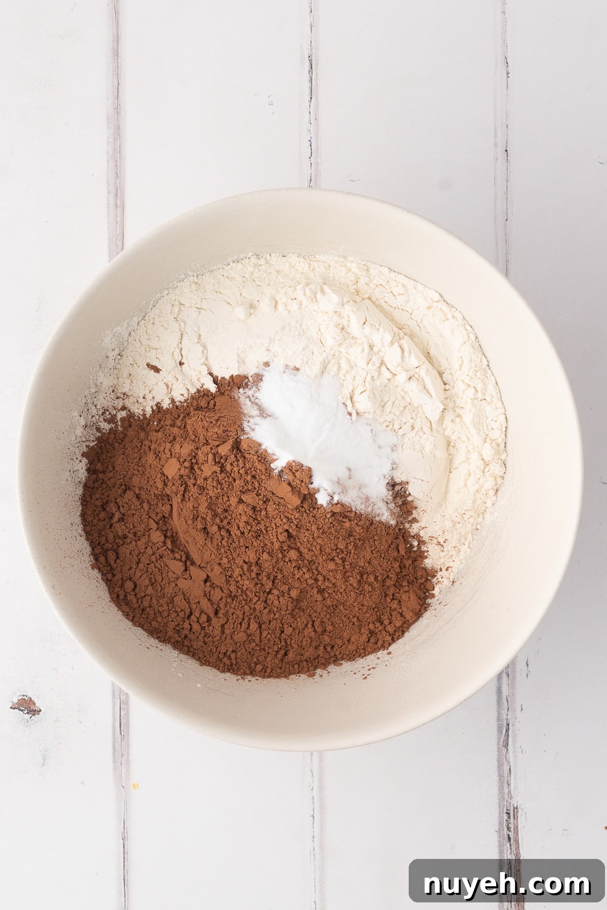 Mixing together dry ingredients including carefully measured cocoa powder together.