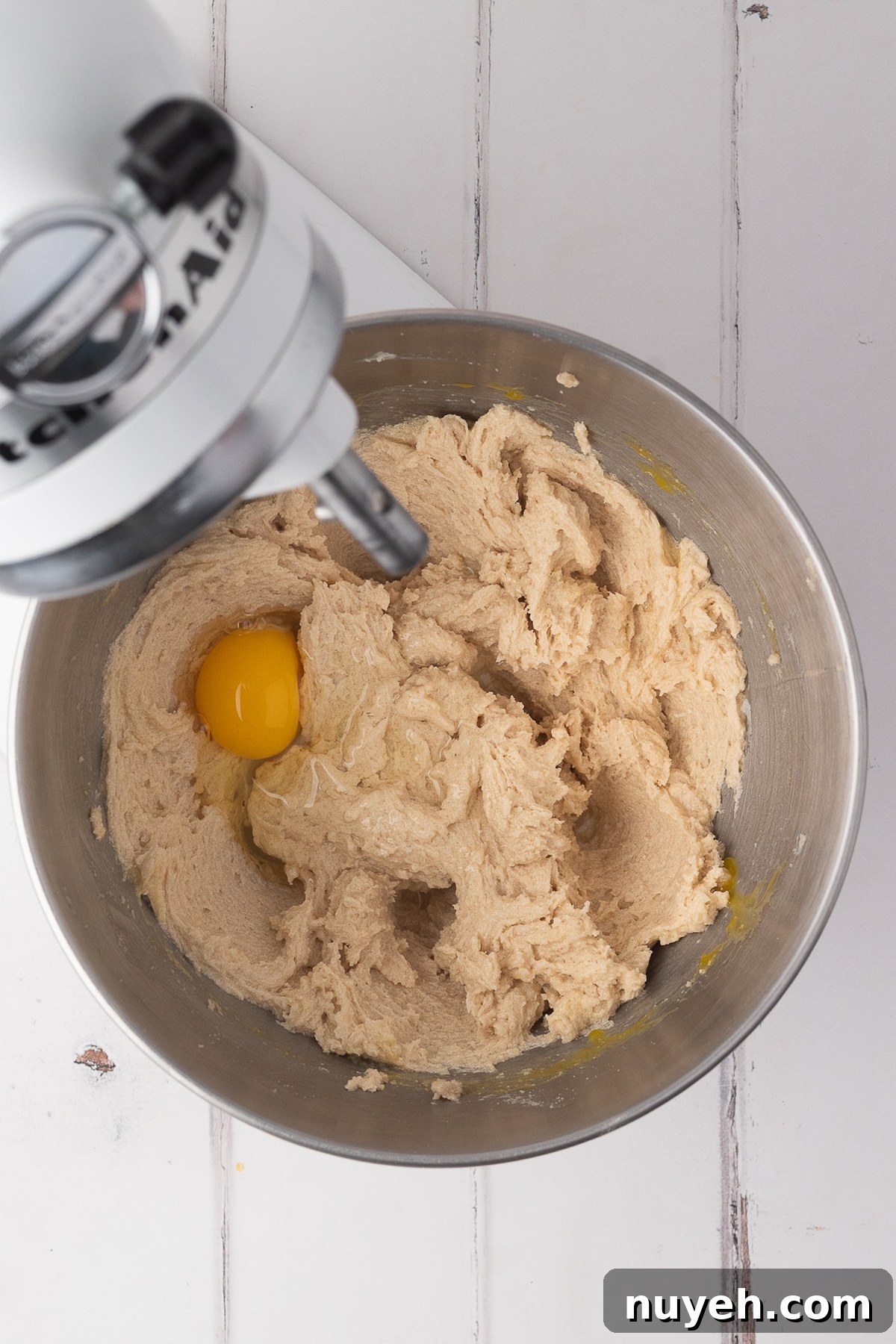A stand mixer whisking together softened butter and sugars and eggs until light and fluffy for cookie dough.