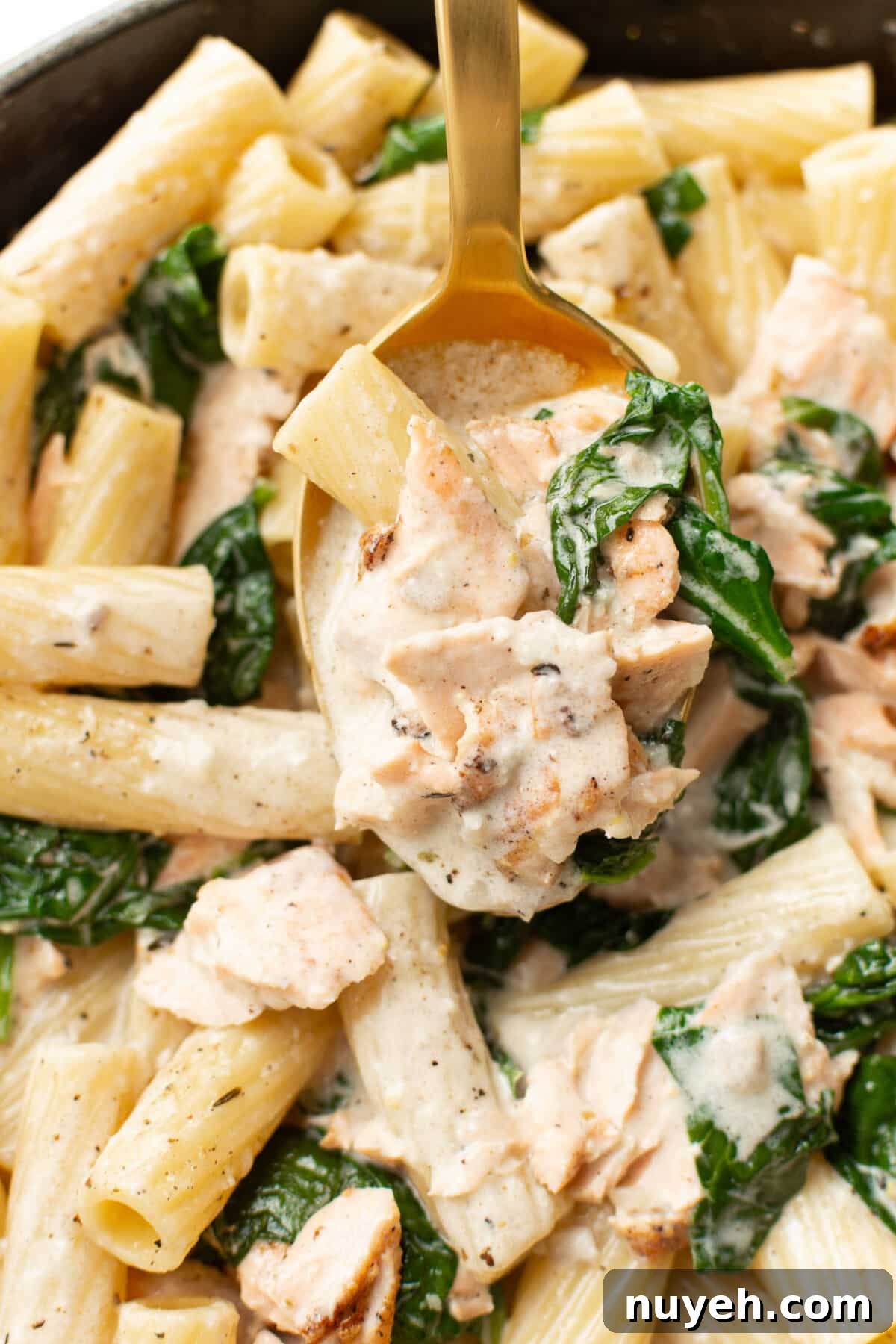 closeup of a serving spoon with lemon spinach salmon pasta