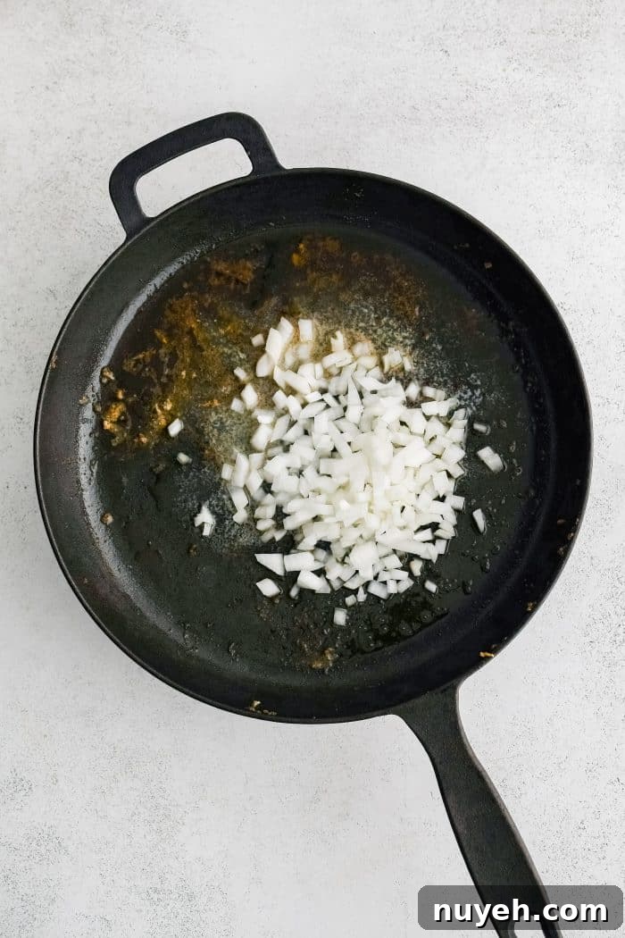 Olive oil and diced white onion in a large cast iron skillet.