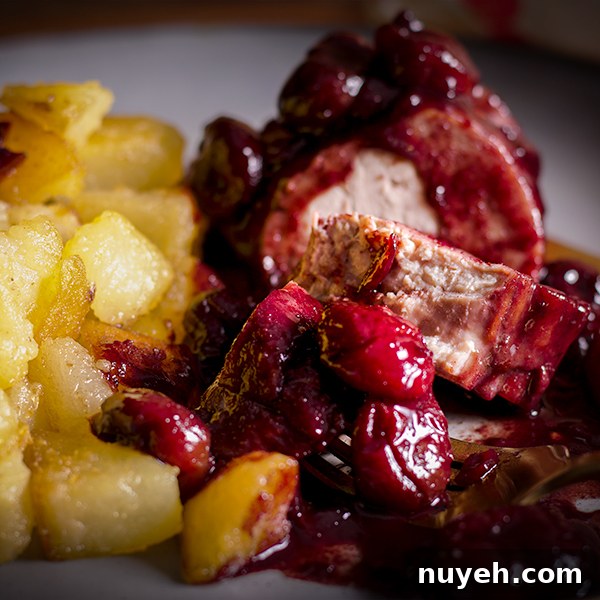 A plate of roast pork with red wine cherry sauce with crispy sautéed potatoes.