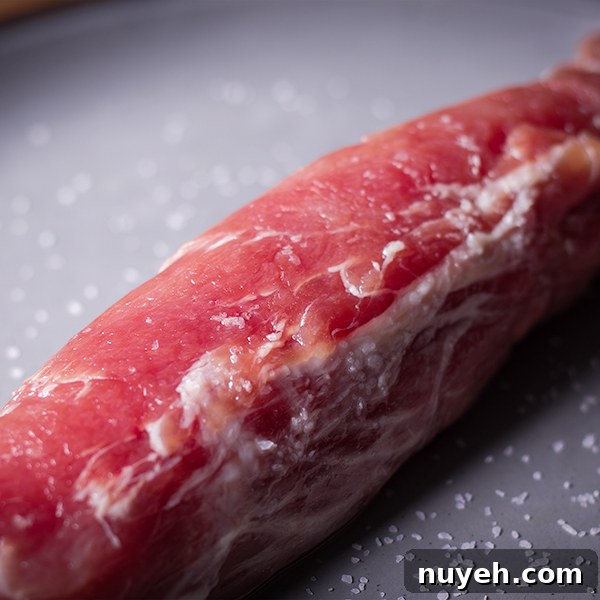 A pork tenderloin on a plate that's been sprinkled with salt.
