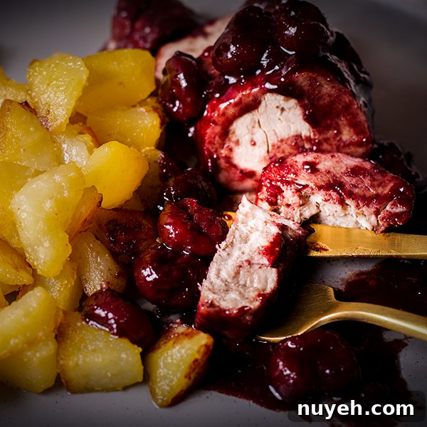 A plate of roast pork with red wine cherry sauce with crispy sautéed potatoes.