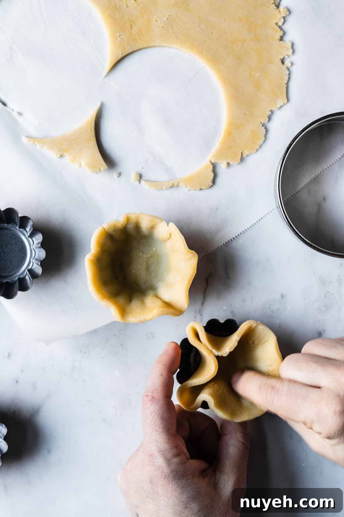 Dough being pressed into small tartlet pans.