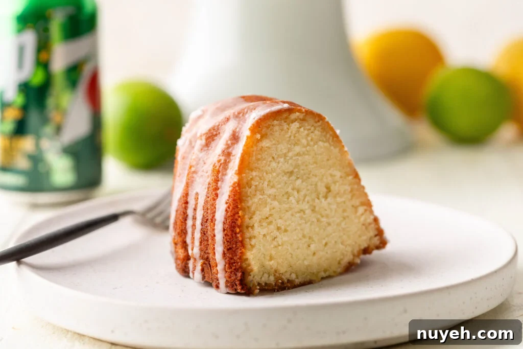 slice of 7 up pound cake on white serving plate with can of 7 up, lemons and limes in the background