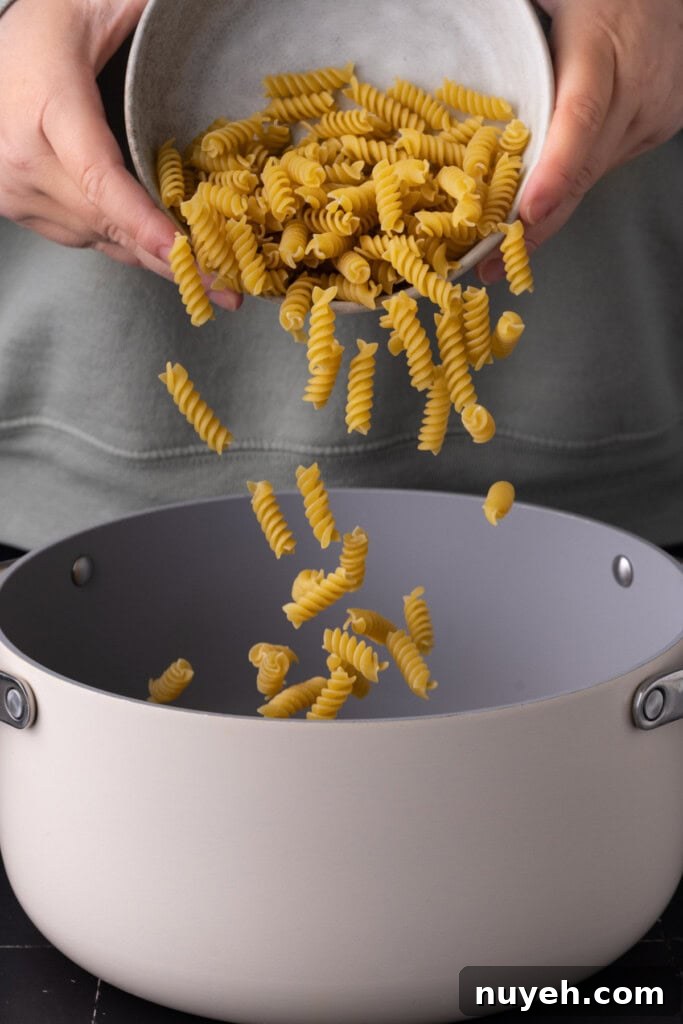 4-Ingredient Canned Tuna and Pesto Pasta Salad 4 Adding rotini to a large pot of boiling water to cook it al dente.