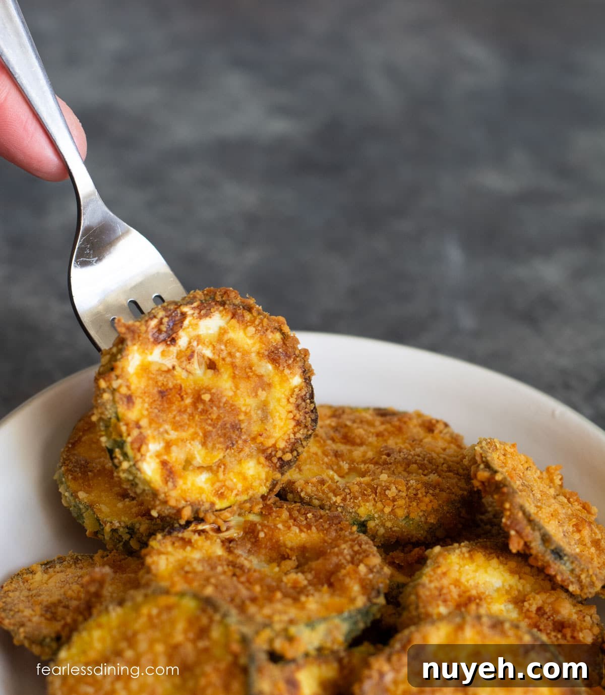 Air Fryer Crispy Gluten-Free Zucchini Chips 7 Picking up a fried zucchini chip from the bowl.