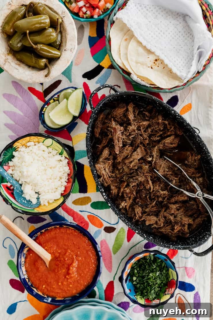 how to set up a serve yourself taco bar with tortillas, suadero style meat, onions, salsa, cilantro and lime wedges on a colorful runner