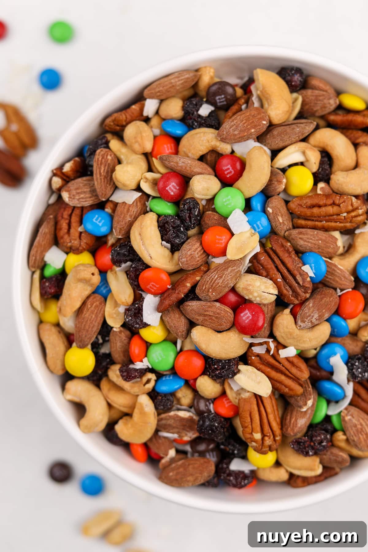 A big white bowl filled with nuts and M&M's.