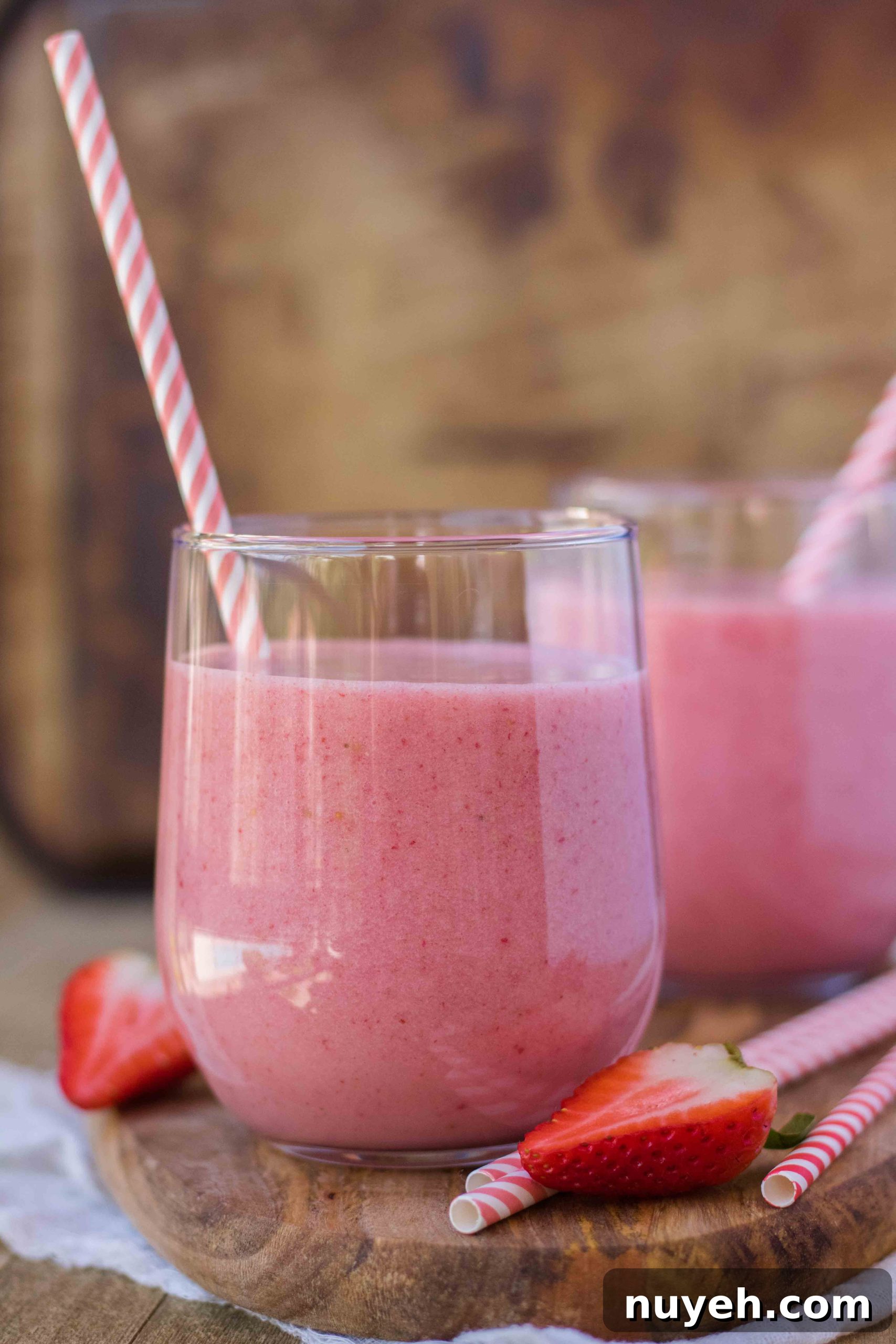 Creamy Strawberry Banana Yogurt Smoothie Recipe 3 Two cups of homemade smoothie with paper straw that's pink and white.
