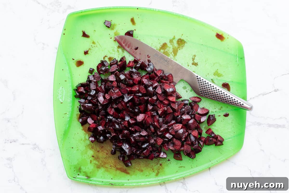 chopped cherries with knife on cutting board.