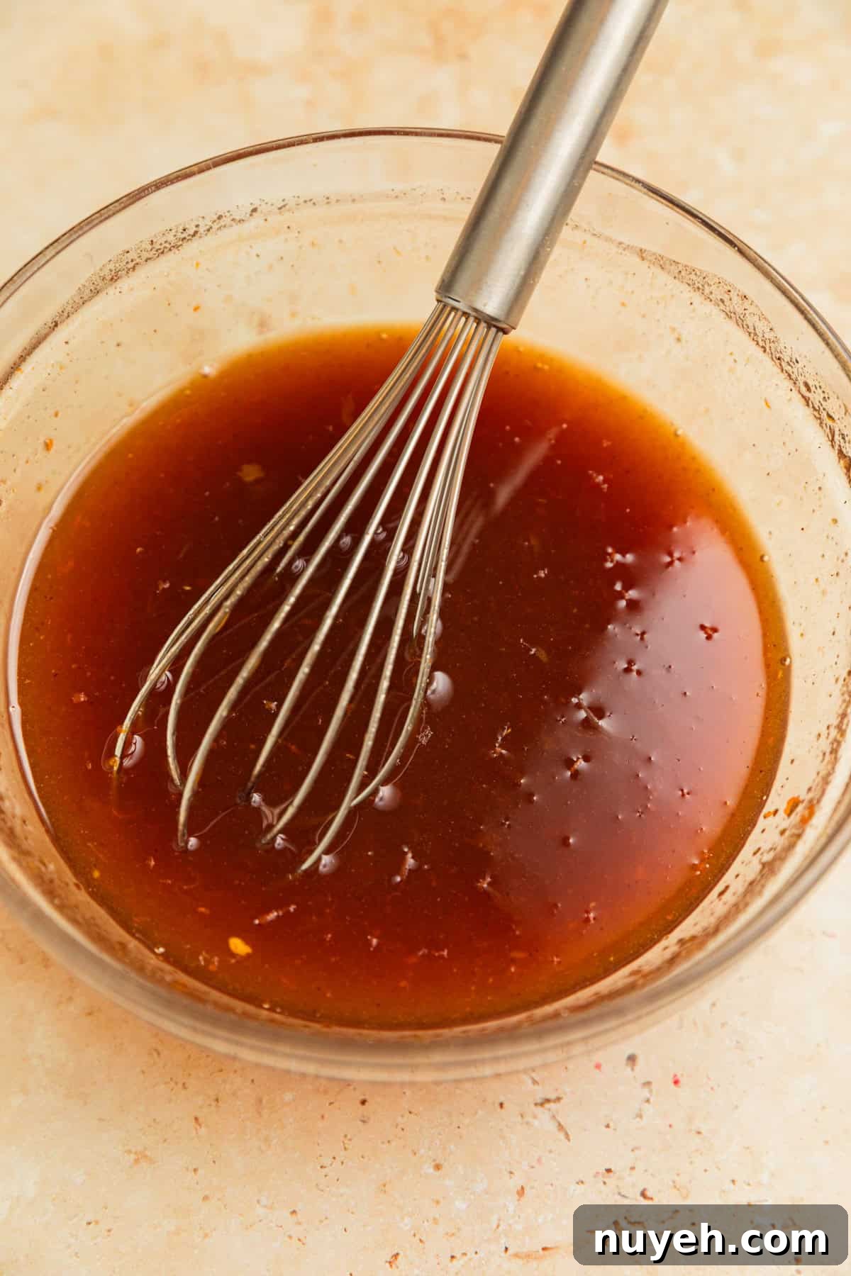 Apricot glaze in bowl with whisk.
